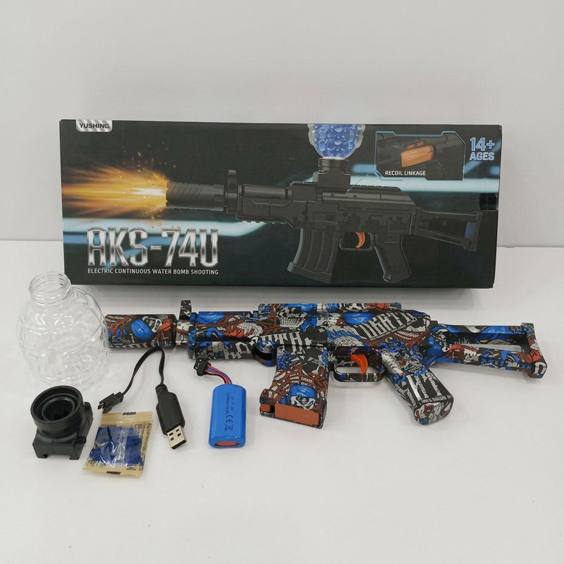 AKS-74U-style water gel blaster rifle beside its box, with soaking bottle, sight attachment, battery, USB cable and gel balls laid out
