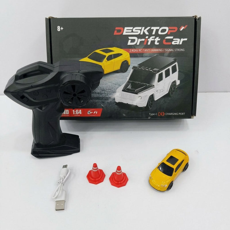 DESKTOP Drift Car box front with the 8+ age mark and 1:64 scale badge, and the yellow mini drift car, remote control, USB cable and two cones laid out in front