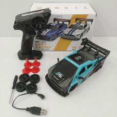 Teal 1:24 scale drift RC car with its remote control, four spare wheels, four traffic cones, a screwdriver and a USB charging cable