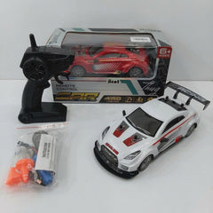 Remote Control Car Racing box front with the 6+ age mark and 4WD / 15 km/h feature icons, and the white GTR-badged car, remote control, spare wheel, cone and battery pack laid out in front