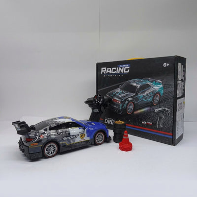 RC drift racing car beside its box, with handheld controller and orange practice cone
