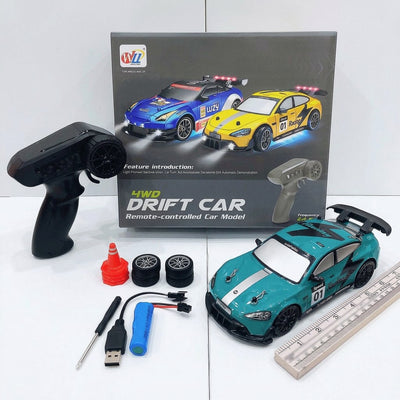 Teal 4WD drift RC car numbered 01, with its remote control, spare wheels, a traffic cone, a battery pack and a ruler for scale