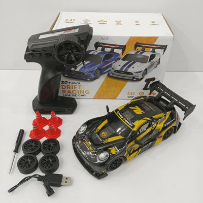 Black and yellow 1:24 scale drift RC car with its remote control, four spare wheels, four traffic cones, a screwdriver and a USB charging cable