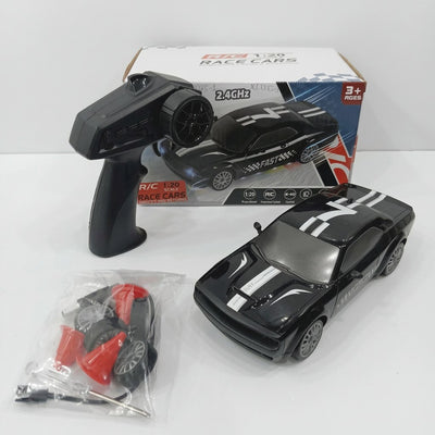 Black 1:20 RC rally race car numbered 7, with its pistol-grip controller, spare wheel, traffic cones and screwdriver, beside the "3+ AGES" box