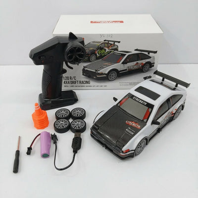 White 1:20 4x4 drift RC car with a checkered-panel livery and rear wing, with its controller, four spare wheels, traffic cone, battery pack and screwdriver, beside the "Striker" box