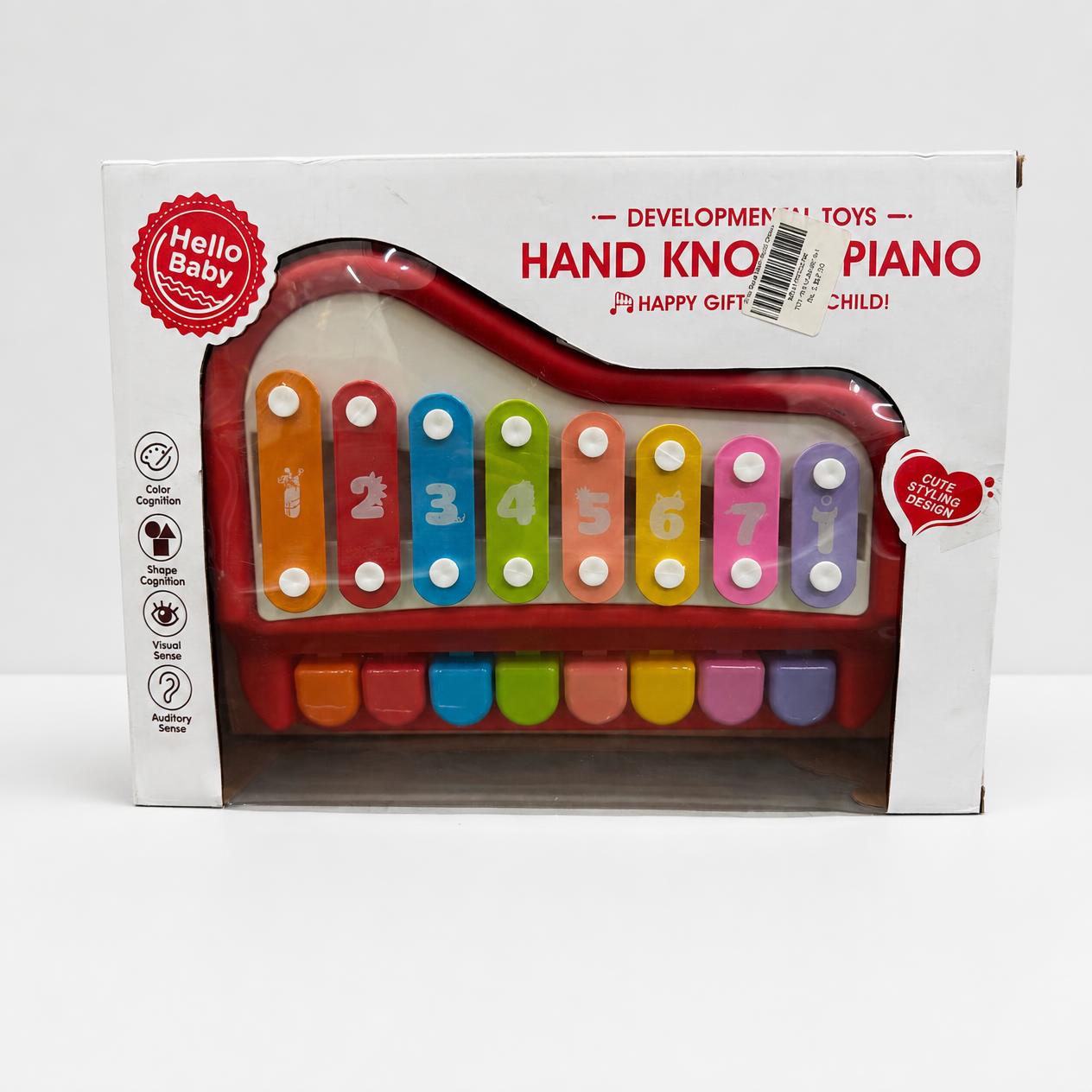 Hand knock piano in red and white inside its window box, eight numbered bars visible